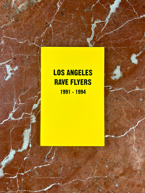 Yellow book with 'Los Angeles Rave Flyers 1991-1994' text on a marbled tan background