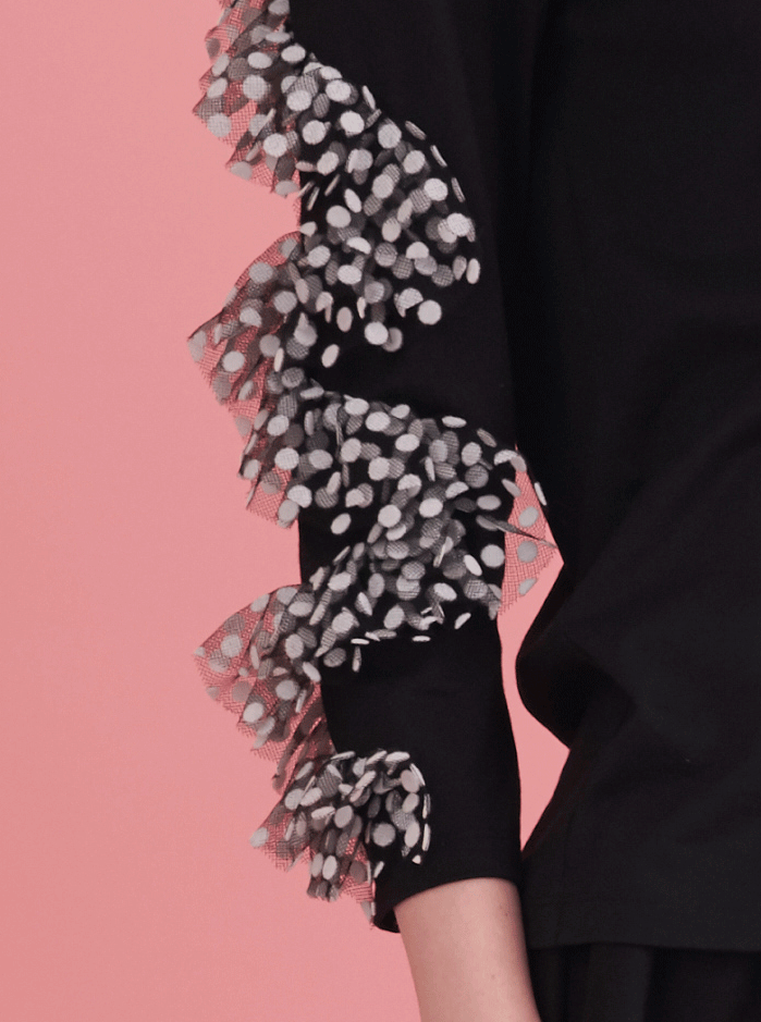 detail of black top with wavy polka dot ruffles on sleeves